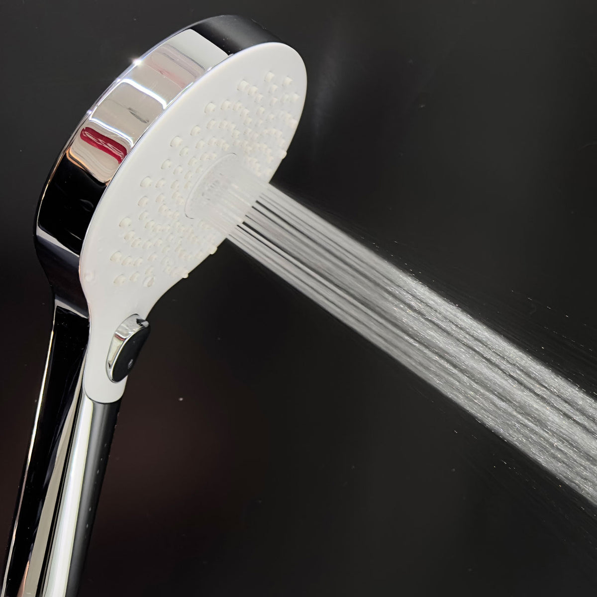 Close-up chrome shower head with white spray plate and multiple jet nozzles