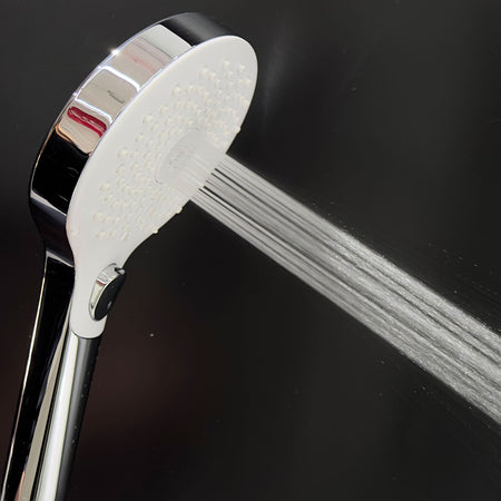 Close-up chrome shower head with white spray plate and multiple jet nozzles