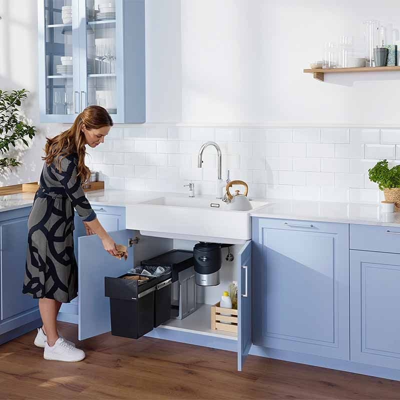 Waste disposal unit installed under sink with black hopper and stainless body