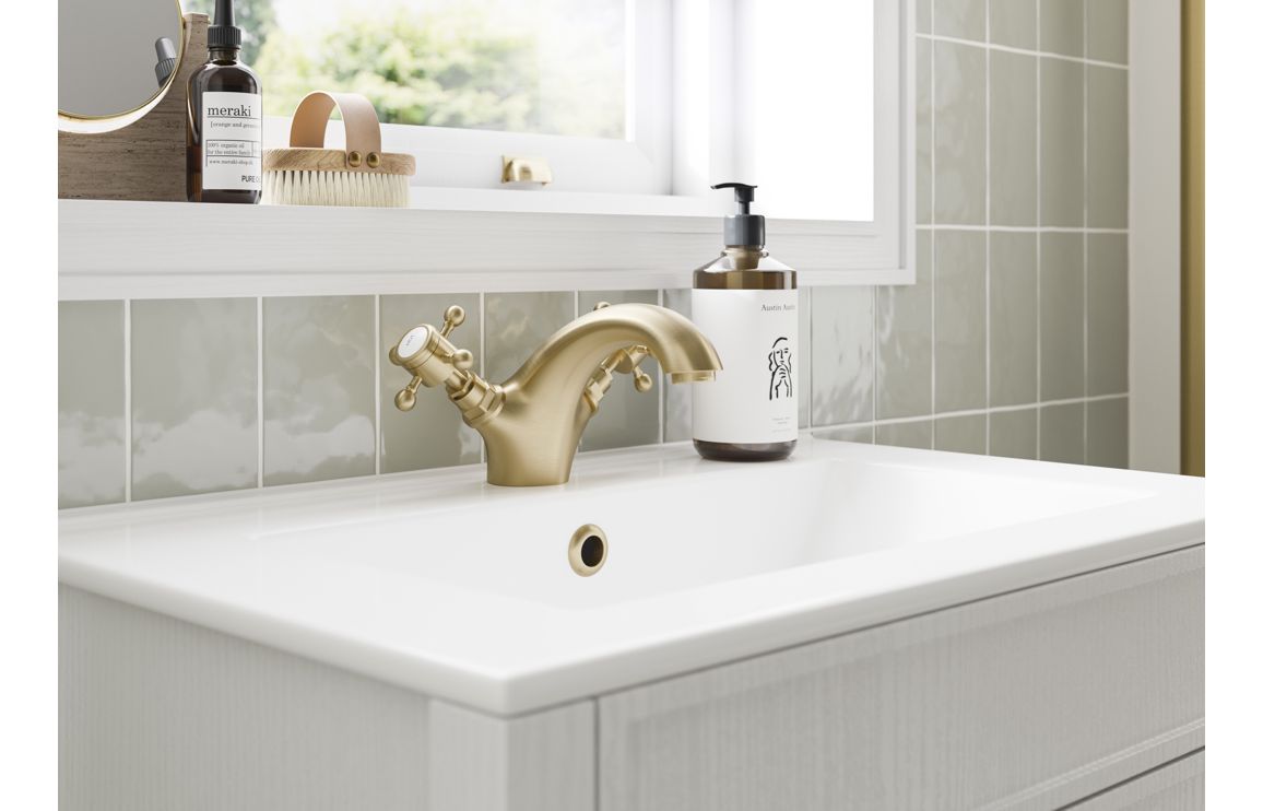 Brushed brass bath pillar tap with cross handles over a white sink