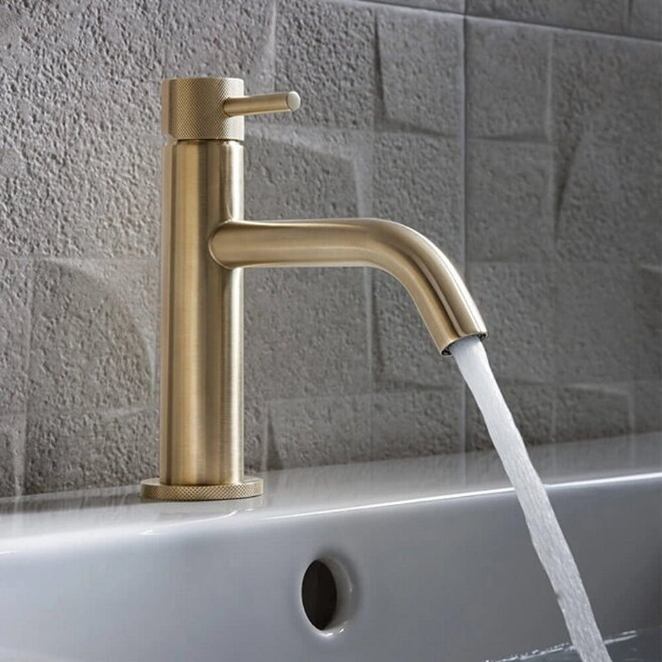Brushed brass basin mixer tap with lever control and curved spout pouring water