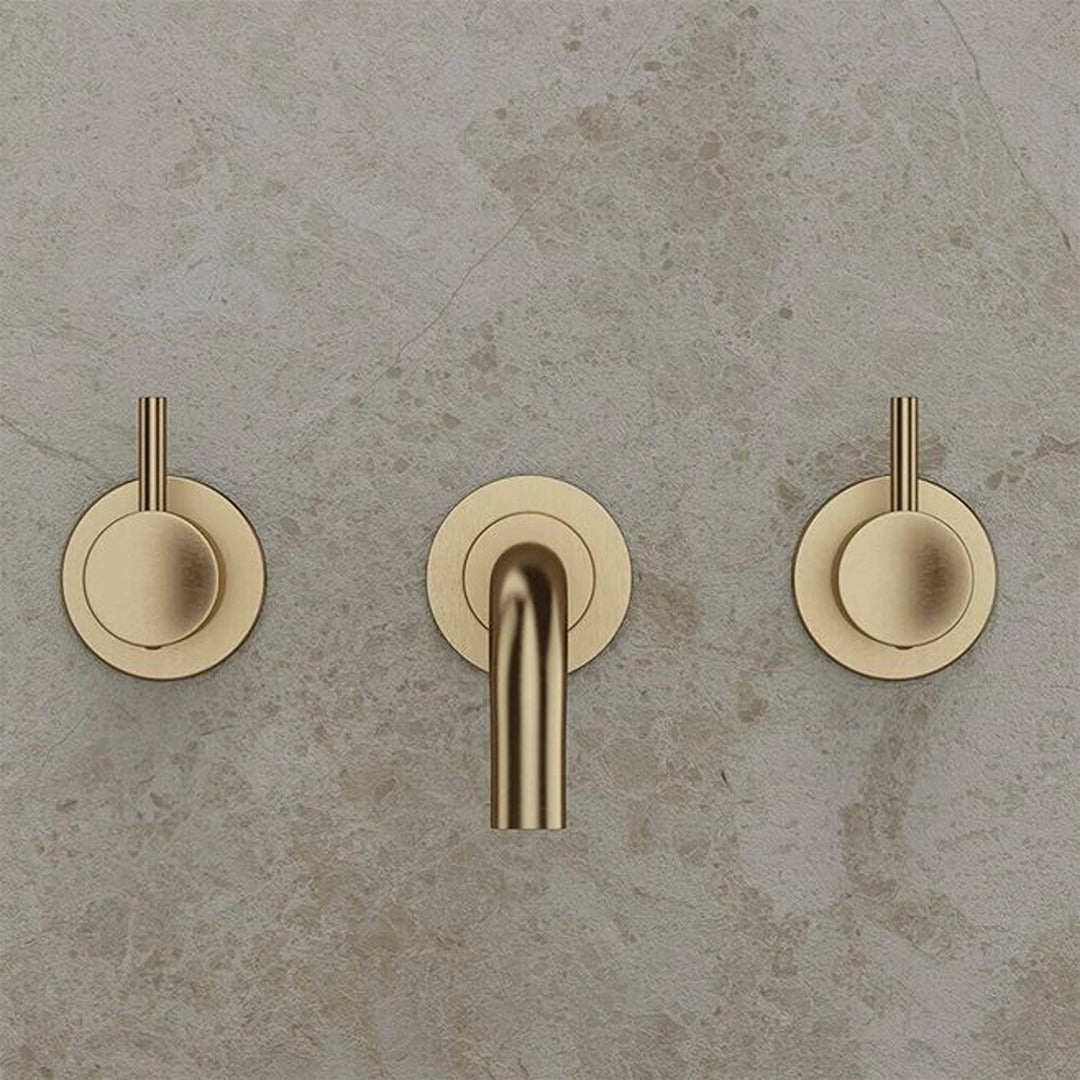 Brushed brass wall-mounted basin mixer with twin lever handles and spout outlet