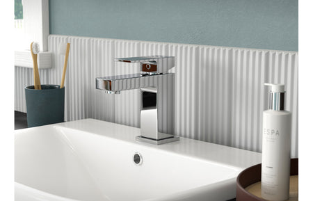Chrome basin mixer tap with rectangular handle mounted on a sink