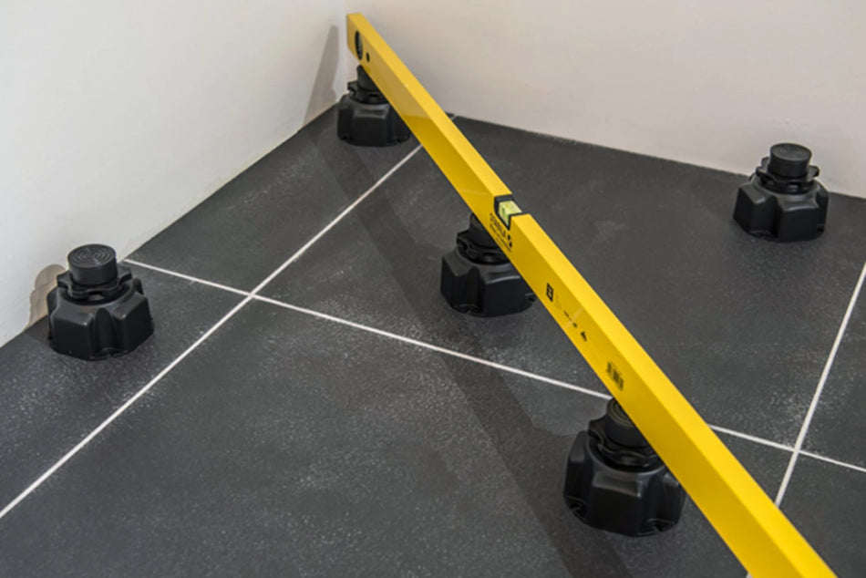 Shower tray riser kit with multiple adjustable black feet for leveling