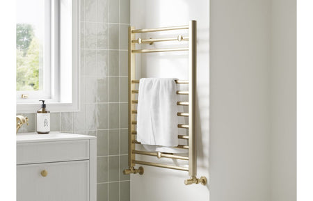 Wall-mounted ladder radiator in brushed brass finish with a folded white towel