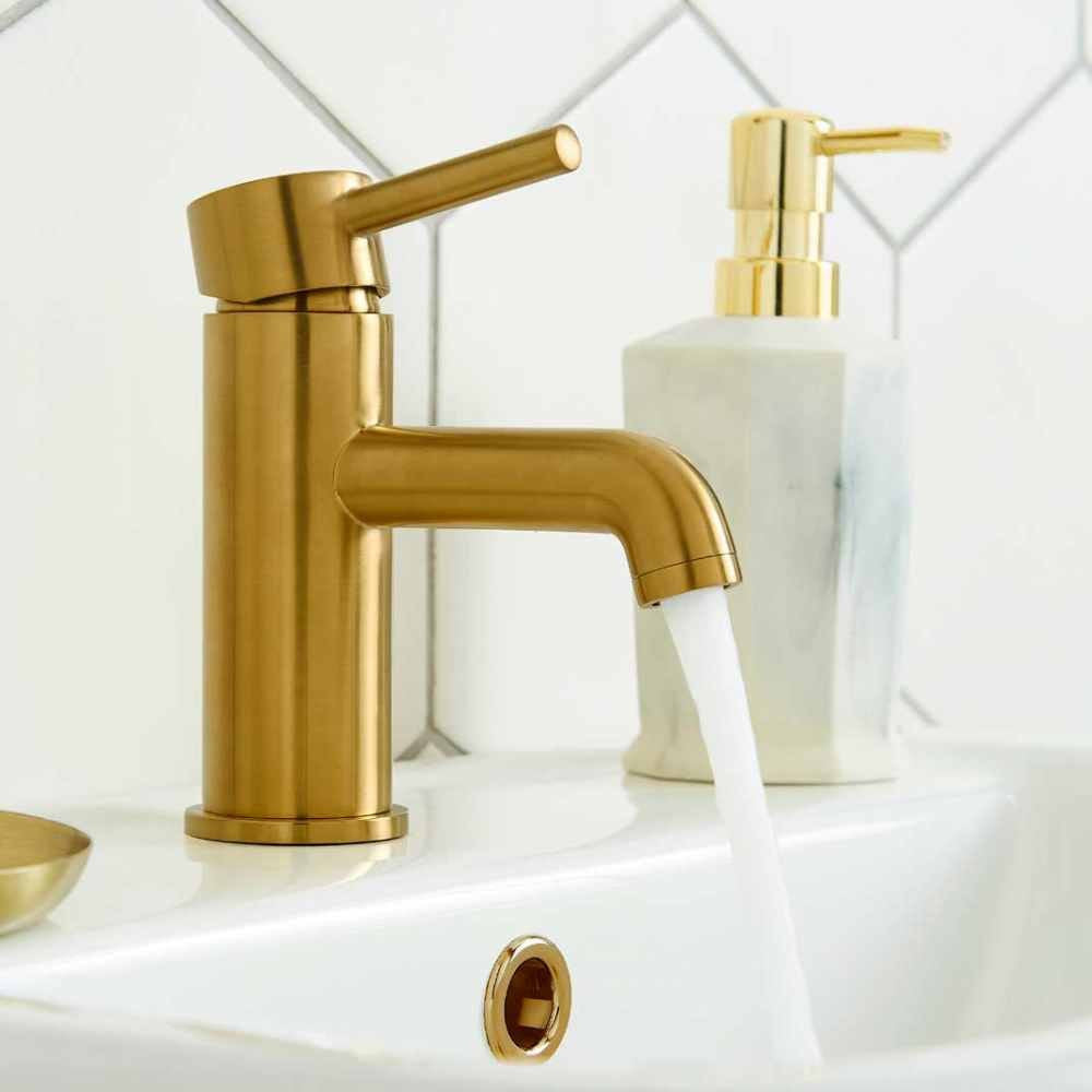 Brushed brass mono basin mixer tap with curved spout and lever on a sink