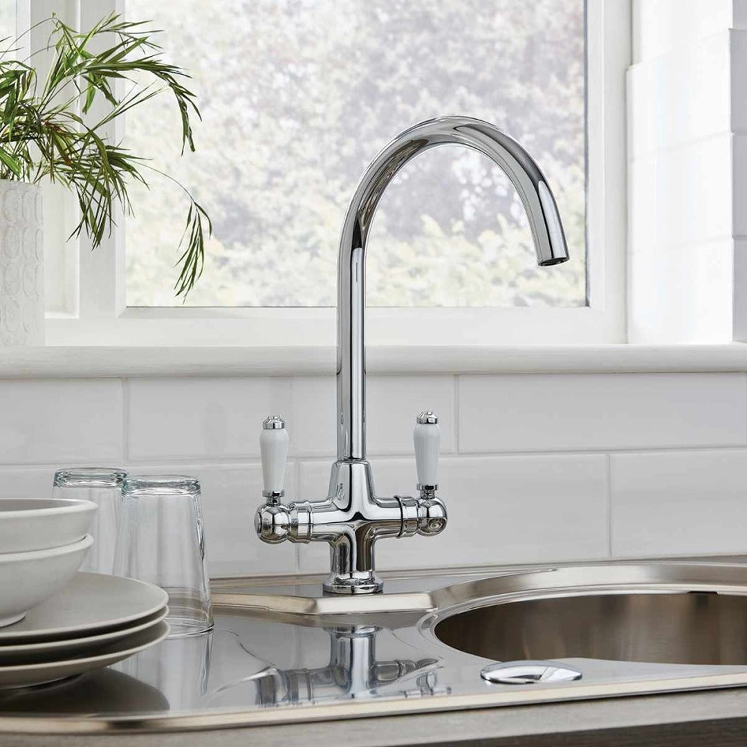 Chrome kitchen mixer tap with arched spout and two lever handles installed in sink