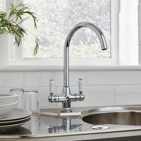 Chrome kitchen mixer tap with arched spout and two lever handles installed in sink