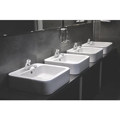 Set of chrome push-button basin taps on wall-mounted vanity sinks